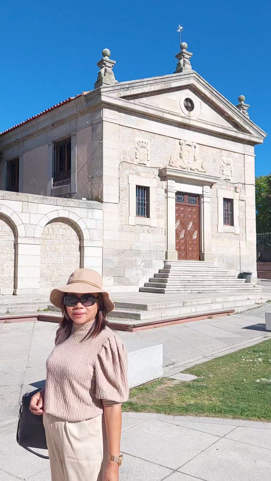 Edna in front of a stone church in Ávila, Spain, from her public pilgrimage post